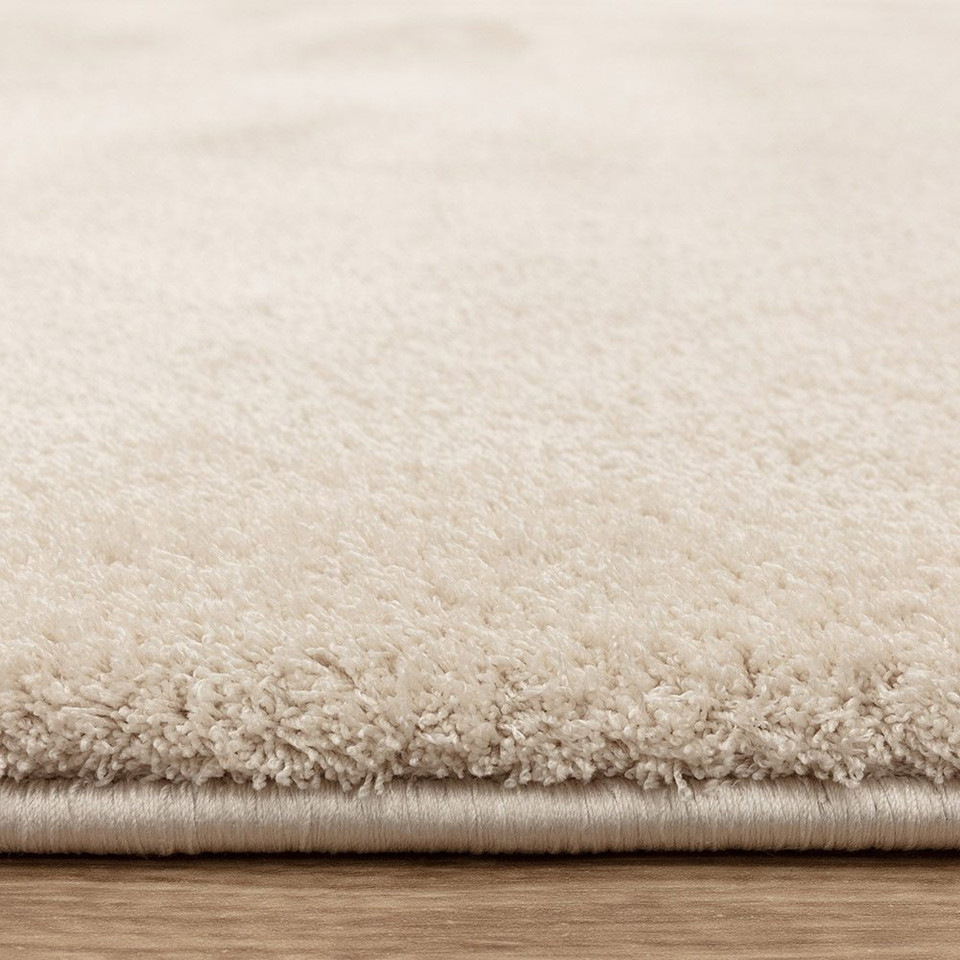 ivory plain shaggy rug closeup edge on wood floor