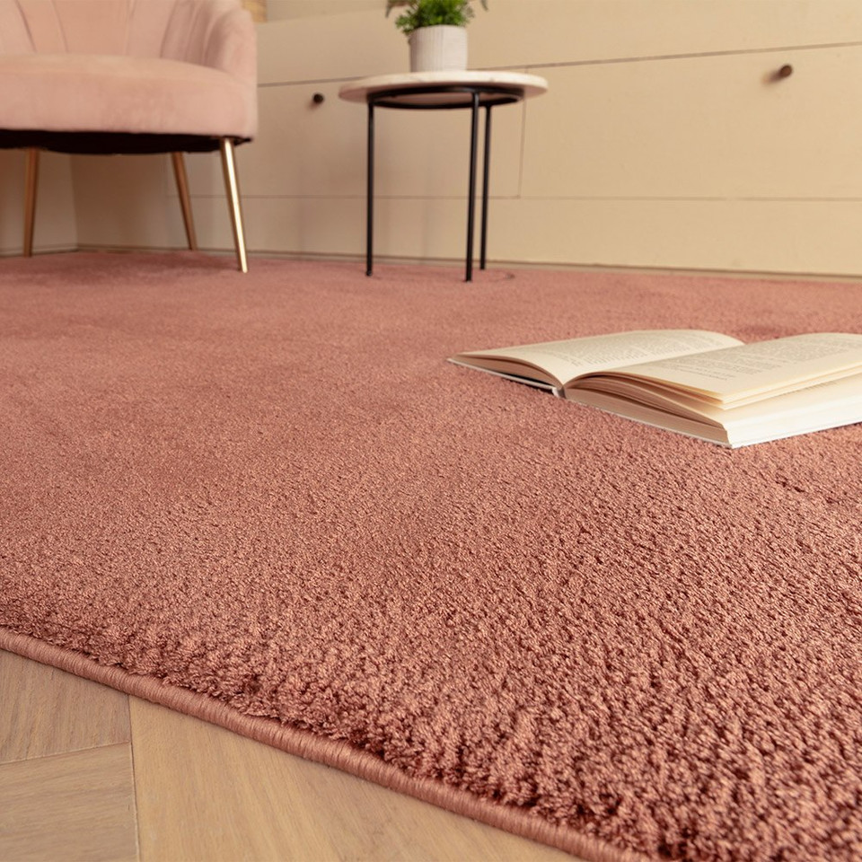 pink plain shaggy rug closeup with a book