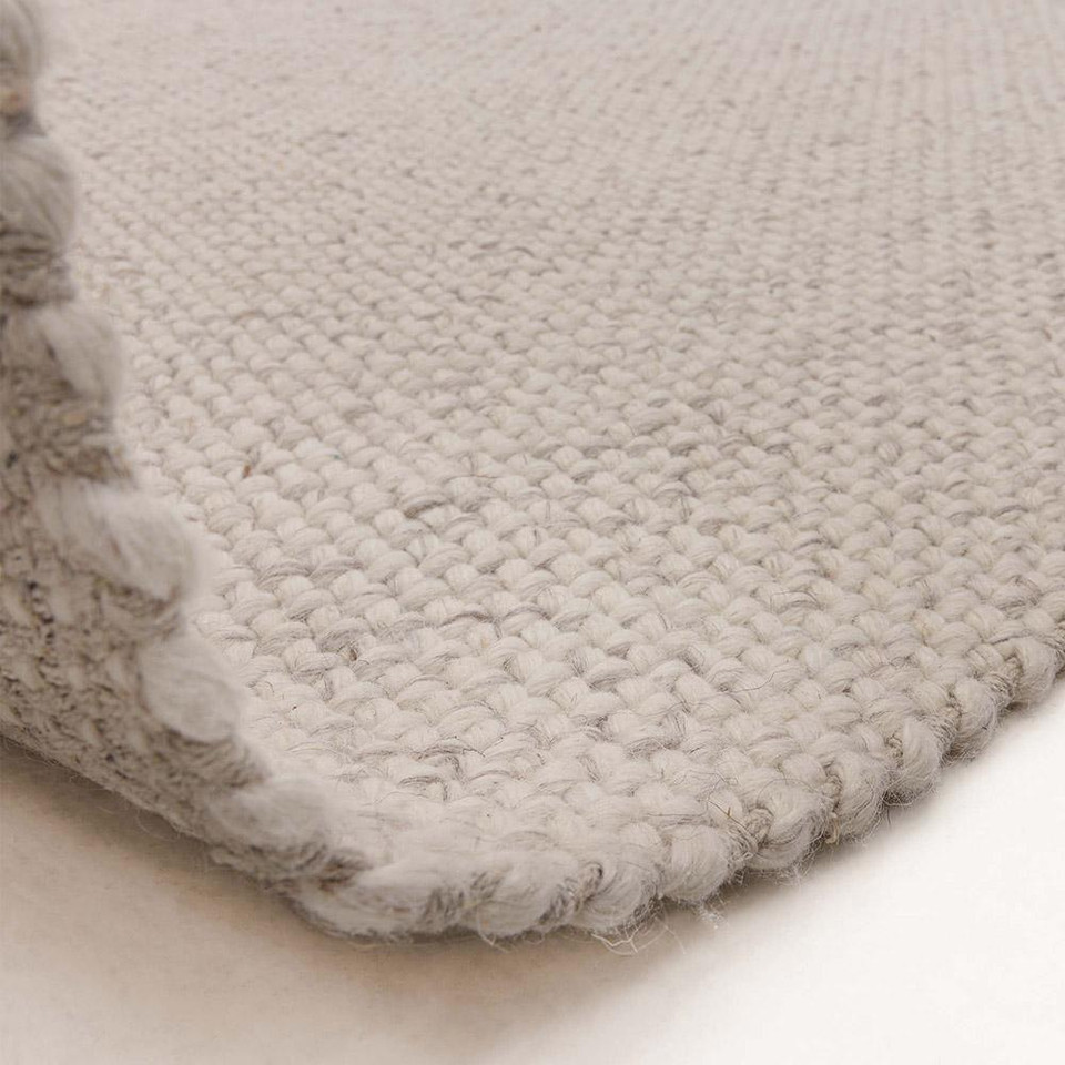 grey plain flatweave rug partial fold on white floor