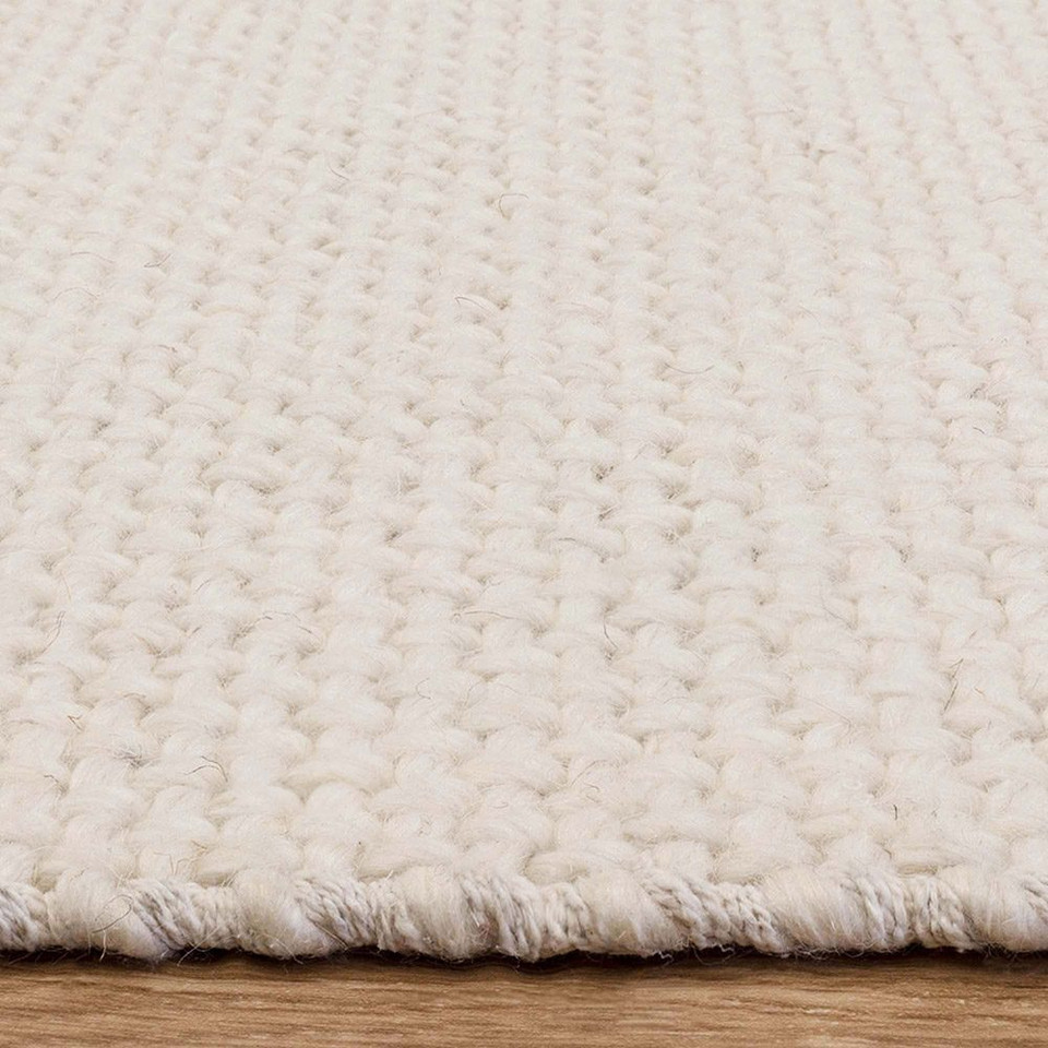 ivory plain flatweave rug closeup edge on wood floor