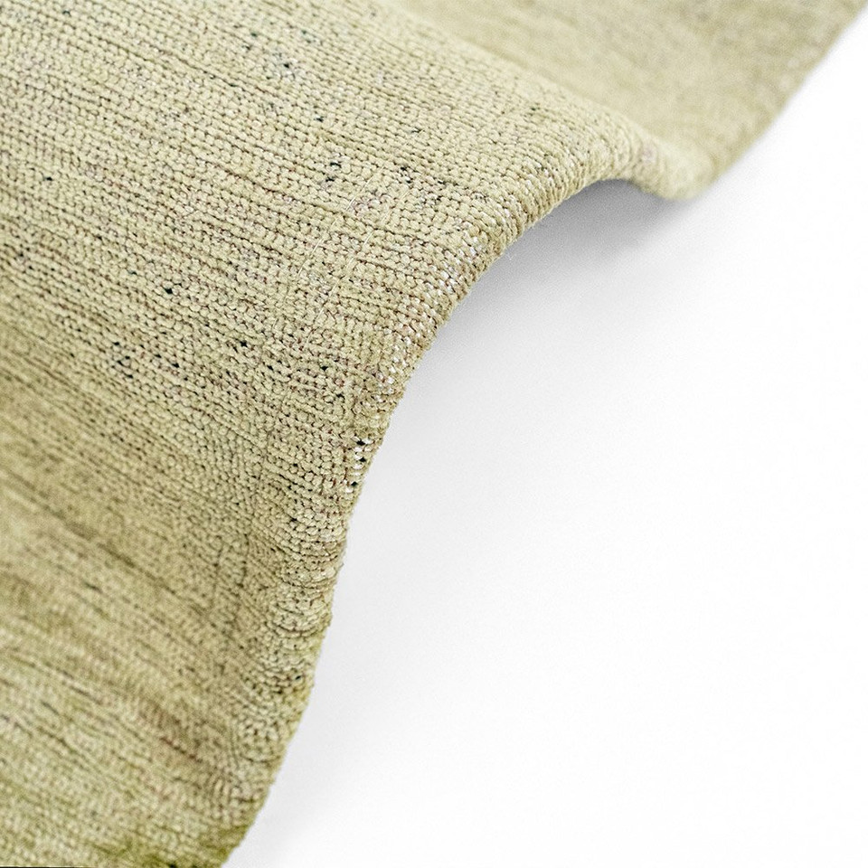green peanut shape rug partially bent on a white floor