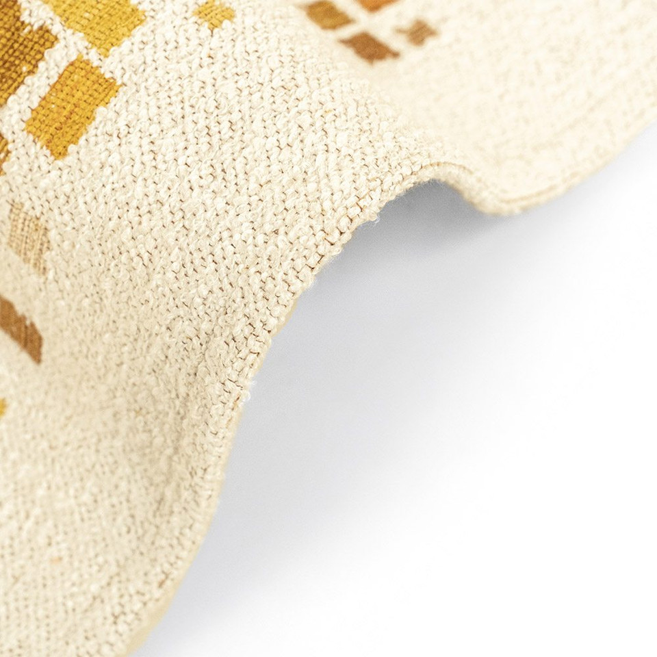yellow abstract rug partially folded on white floor