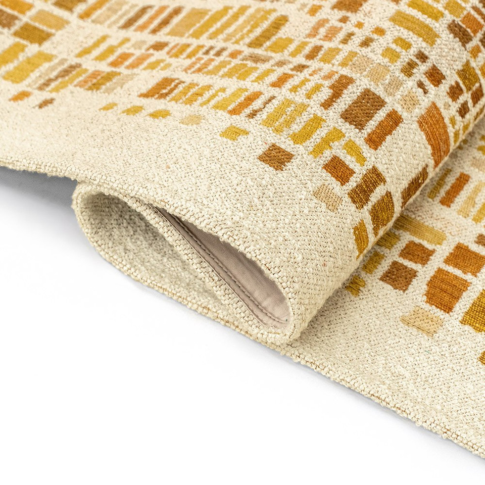 yellow abstract rug partially folded on white floor