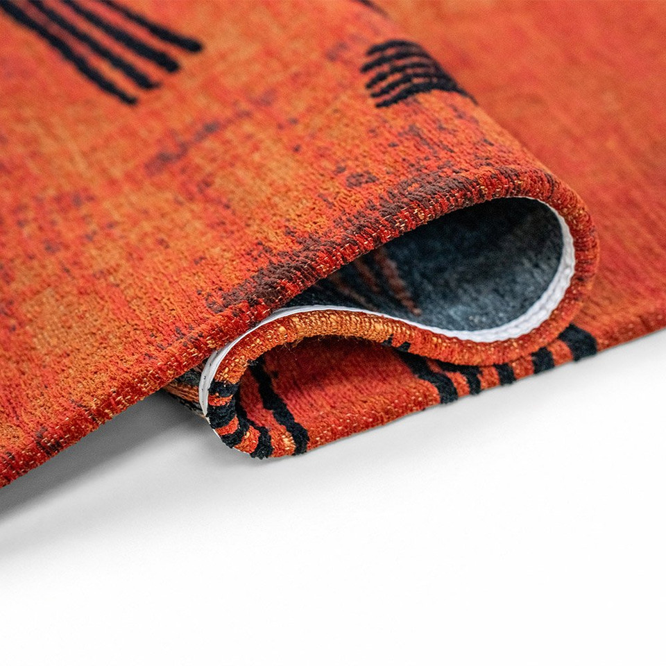 orange abstract rug folded on white floor
