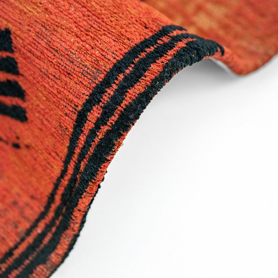 orange abstract rug folded on white floor