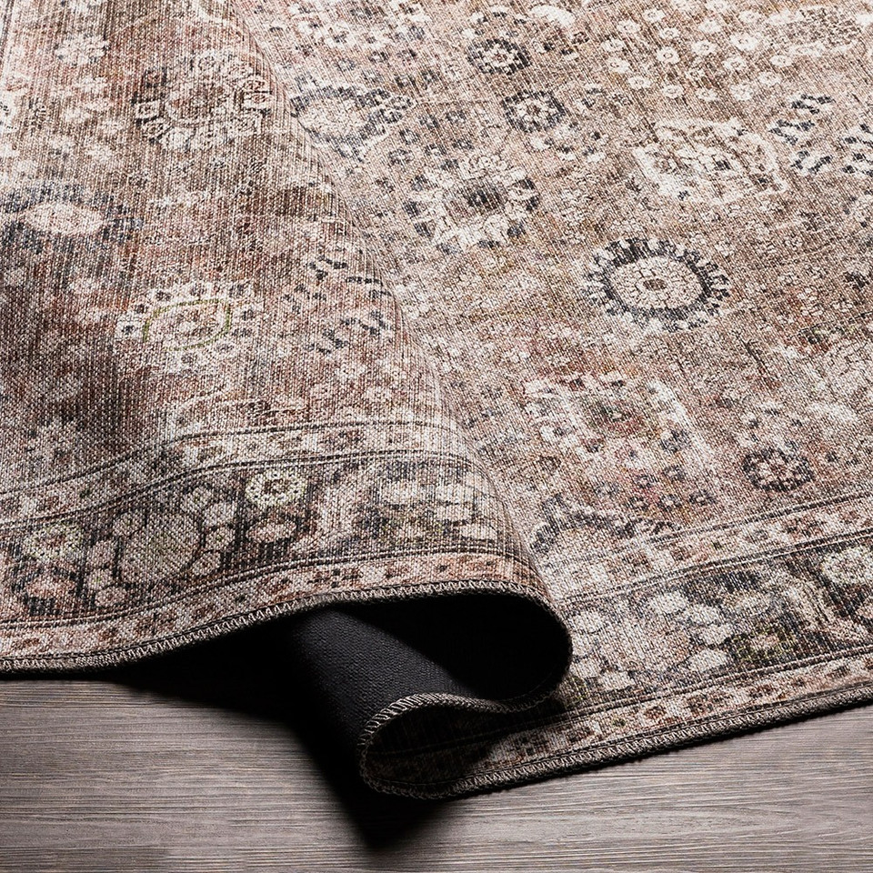 brown traditional rug partially folded on wood floor