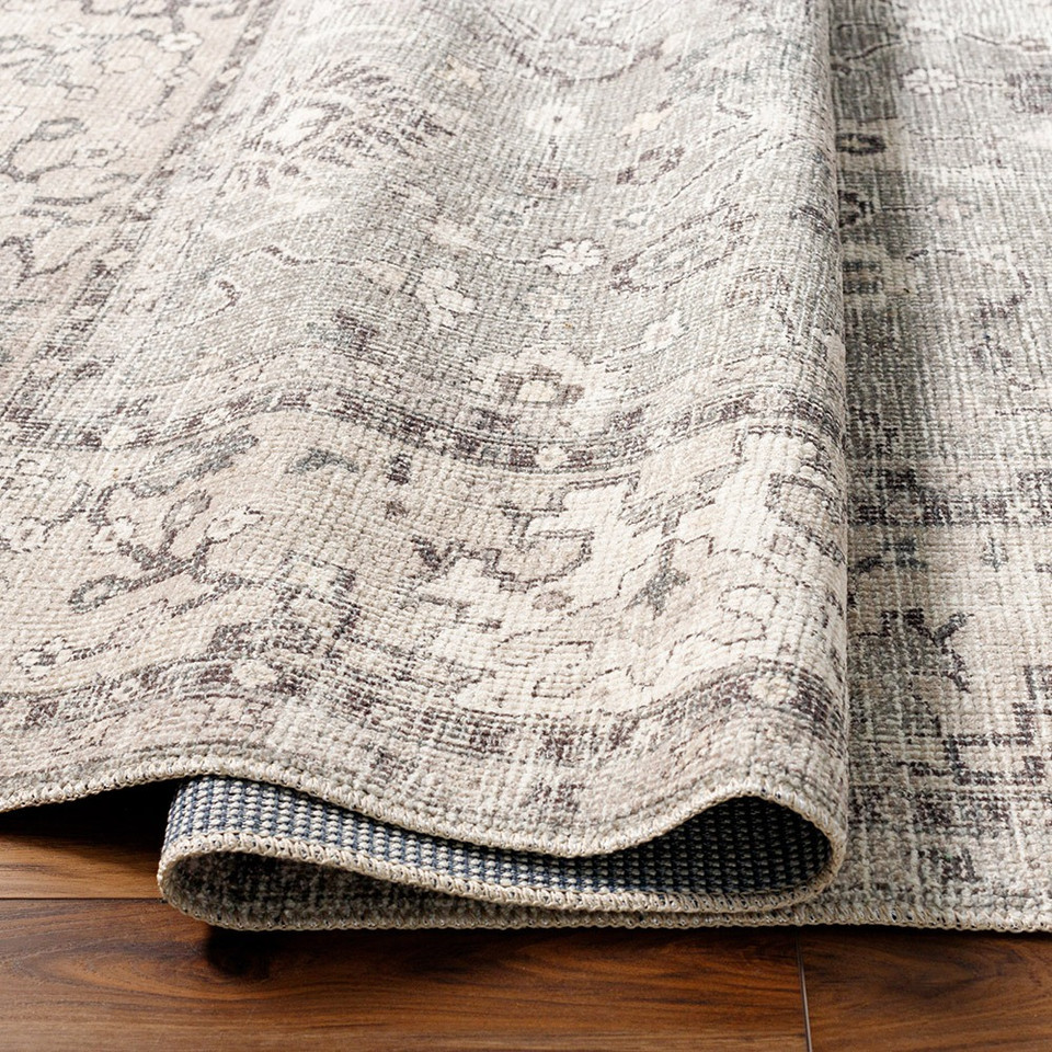brown traditional rug partially folded on wood floor