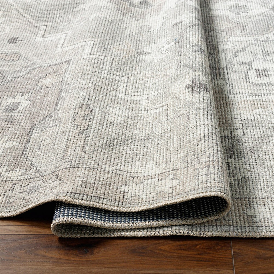 brown traditional rug partially folded on wood floor