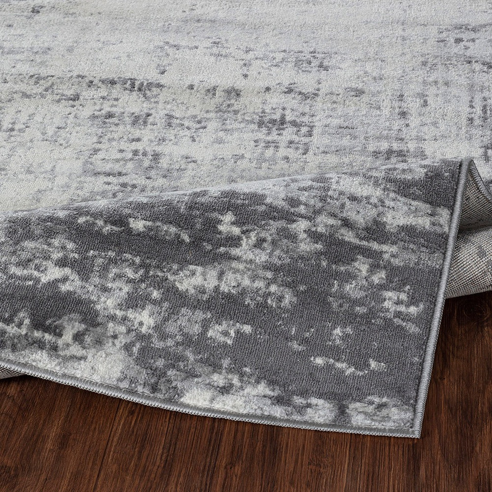 grey abstract rug folded on wood floor