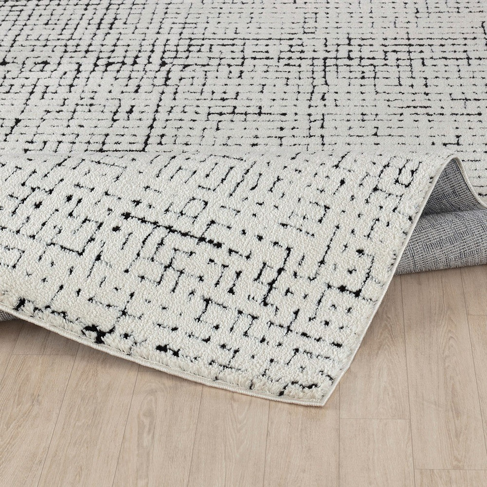 ivory black scandi rug folded on wood floor