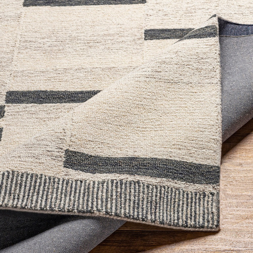 beige striped wool rug folded on wood floor
