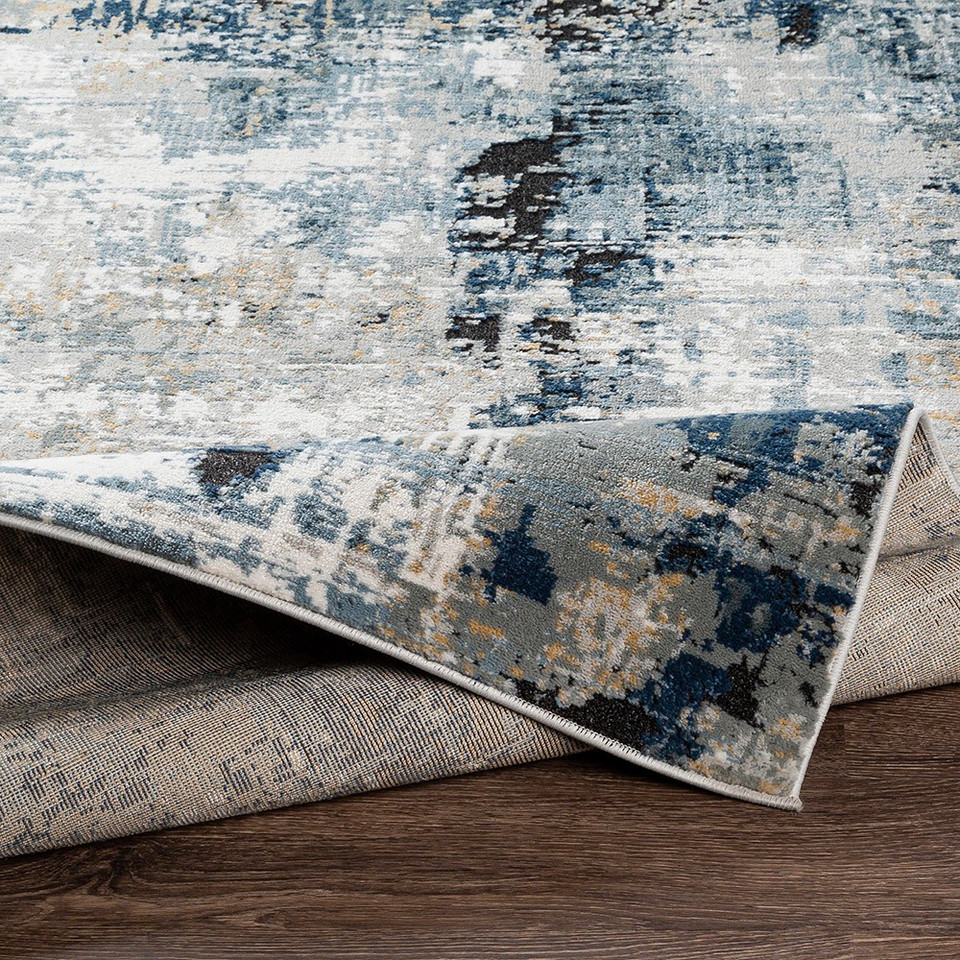 blue abstract rug folded on wood floor