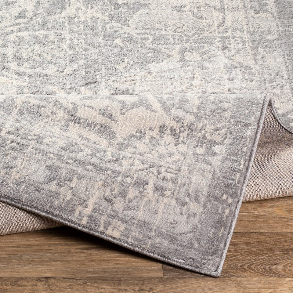grey traditional rug folded on wood floor