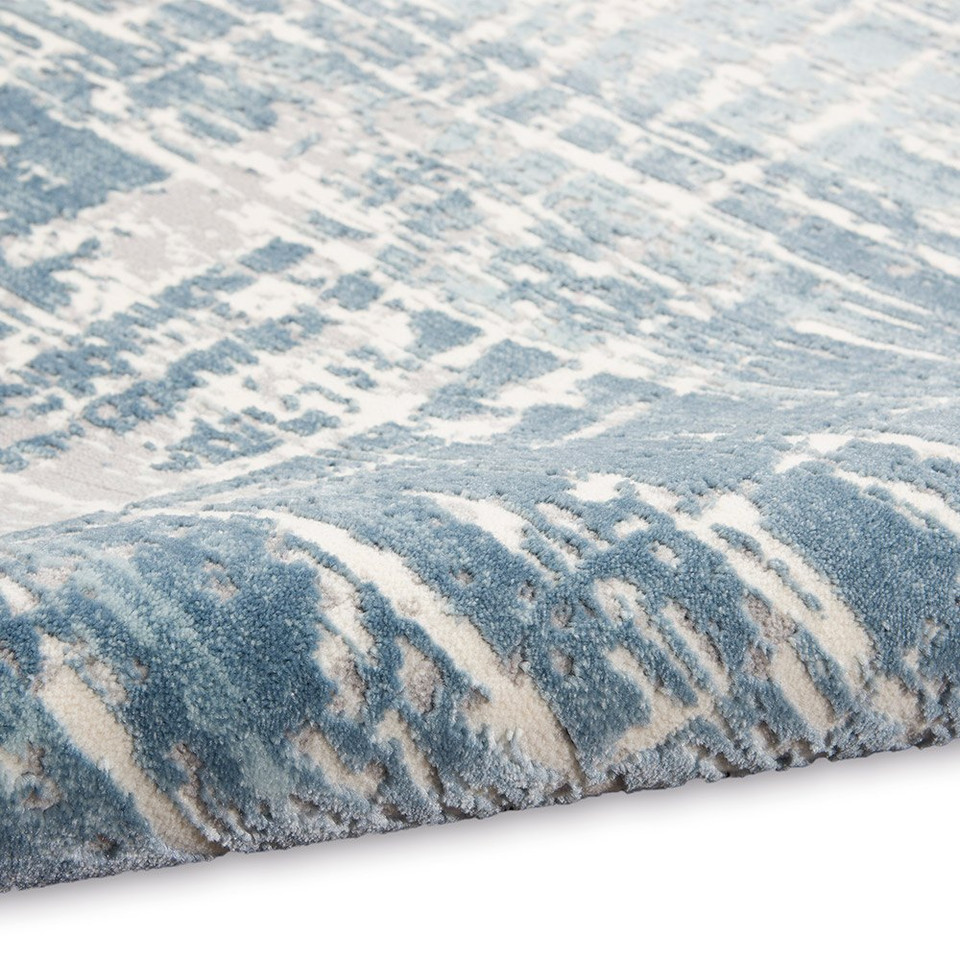 ivory seaglass calvin klein rug partially rolled on white floor