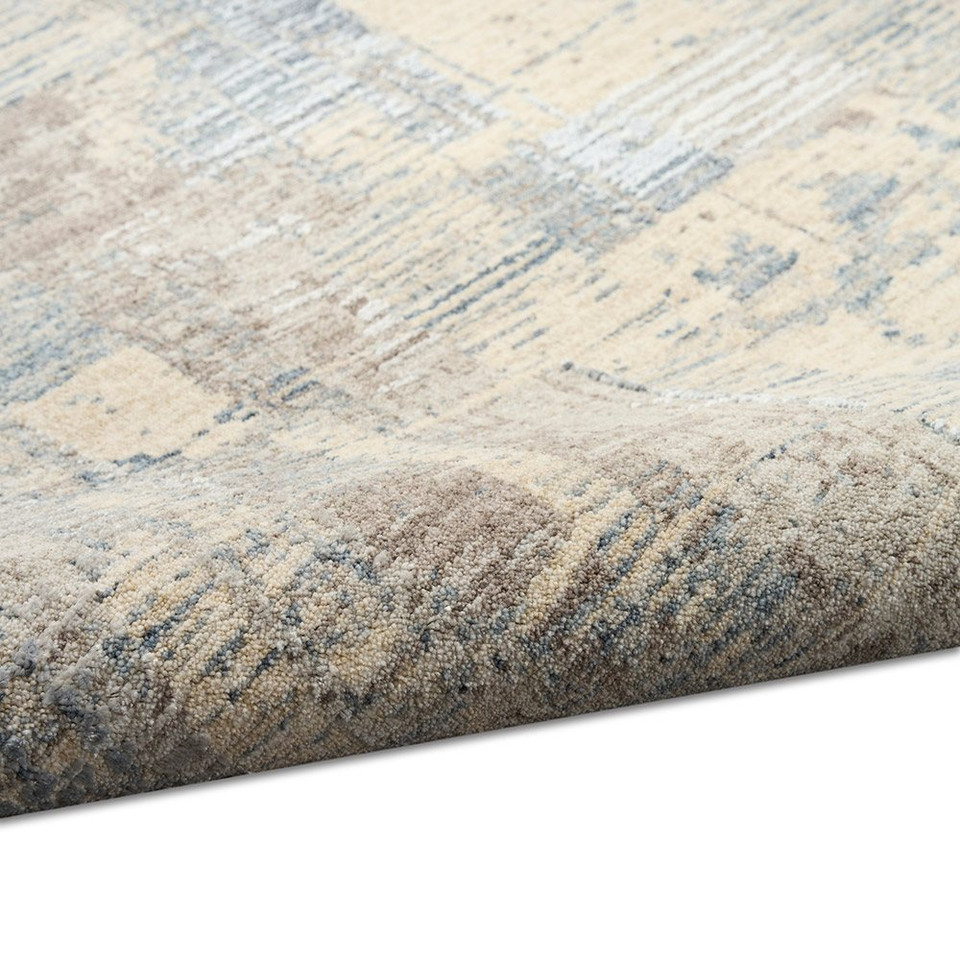 blue beige calvin klein rug partially rolled on white floor