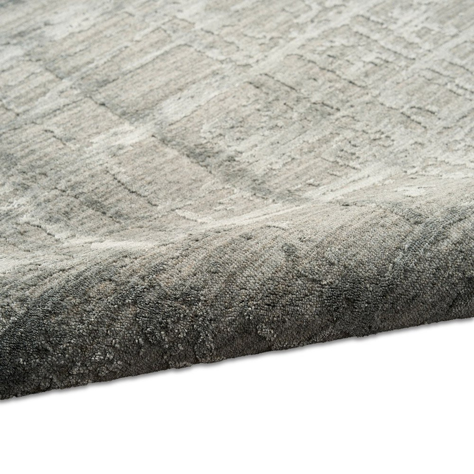 slate calvin klein rug partially rolled on white floor