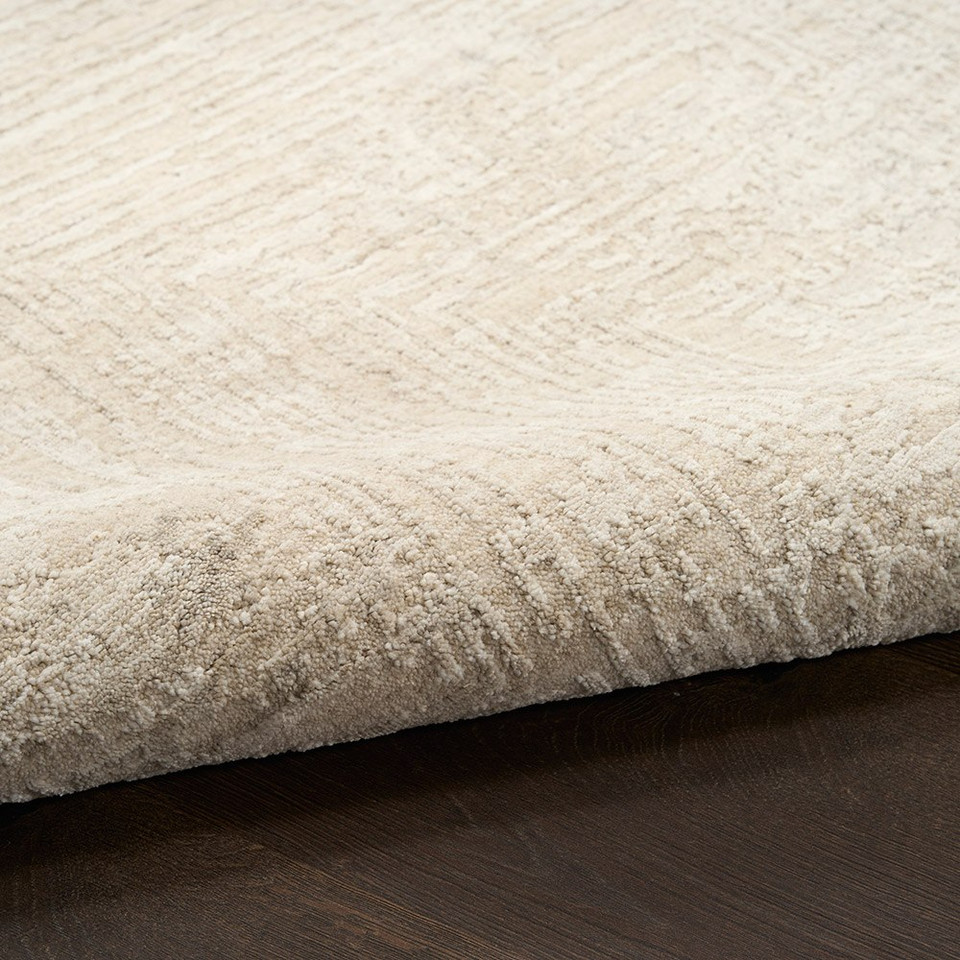 ivory beige abstract rug partially rolled on wood floor