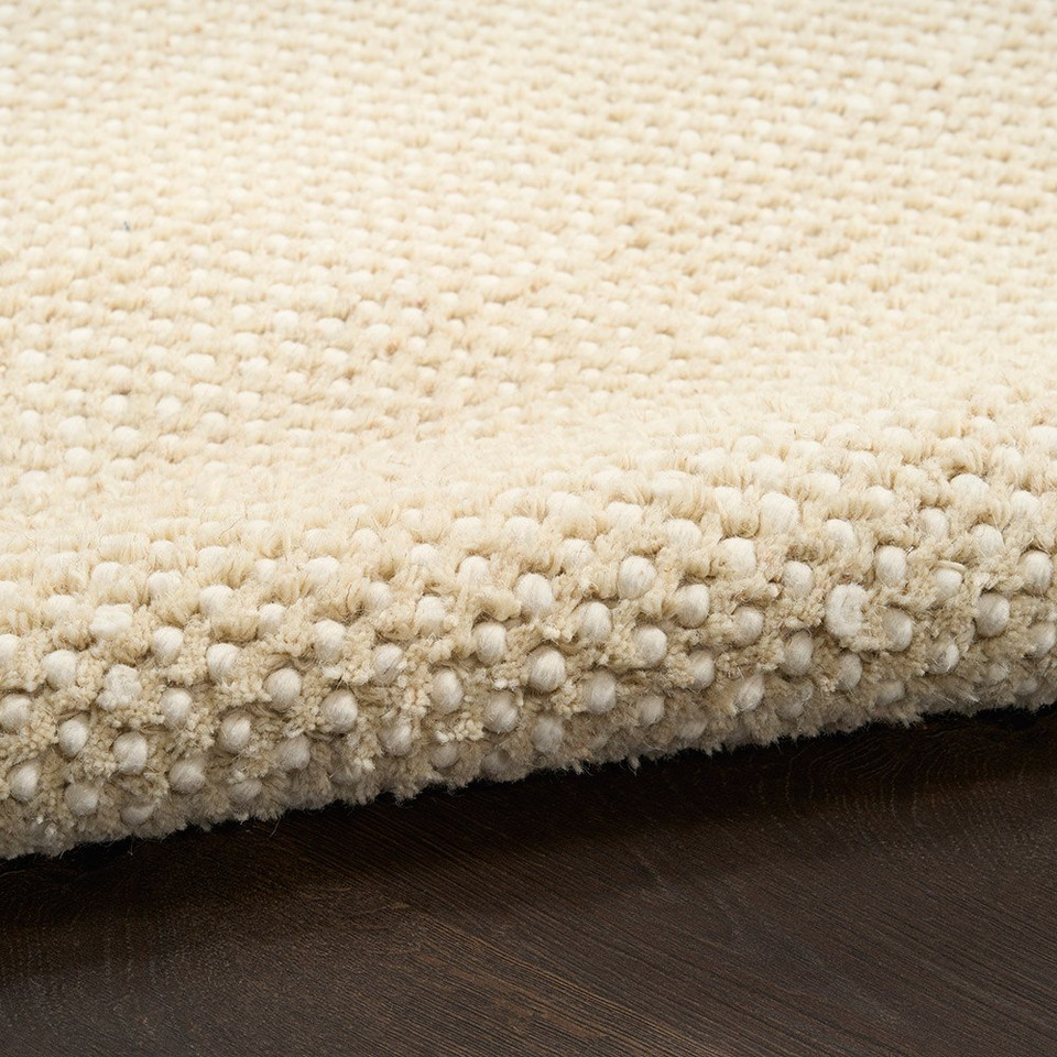 ivory beige rug partially rolled on wood floor