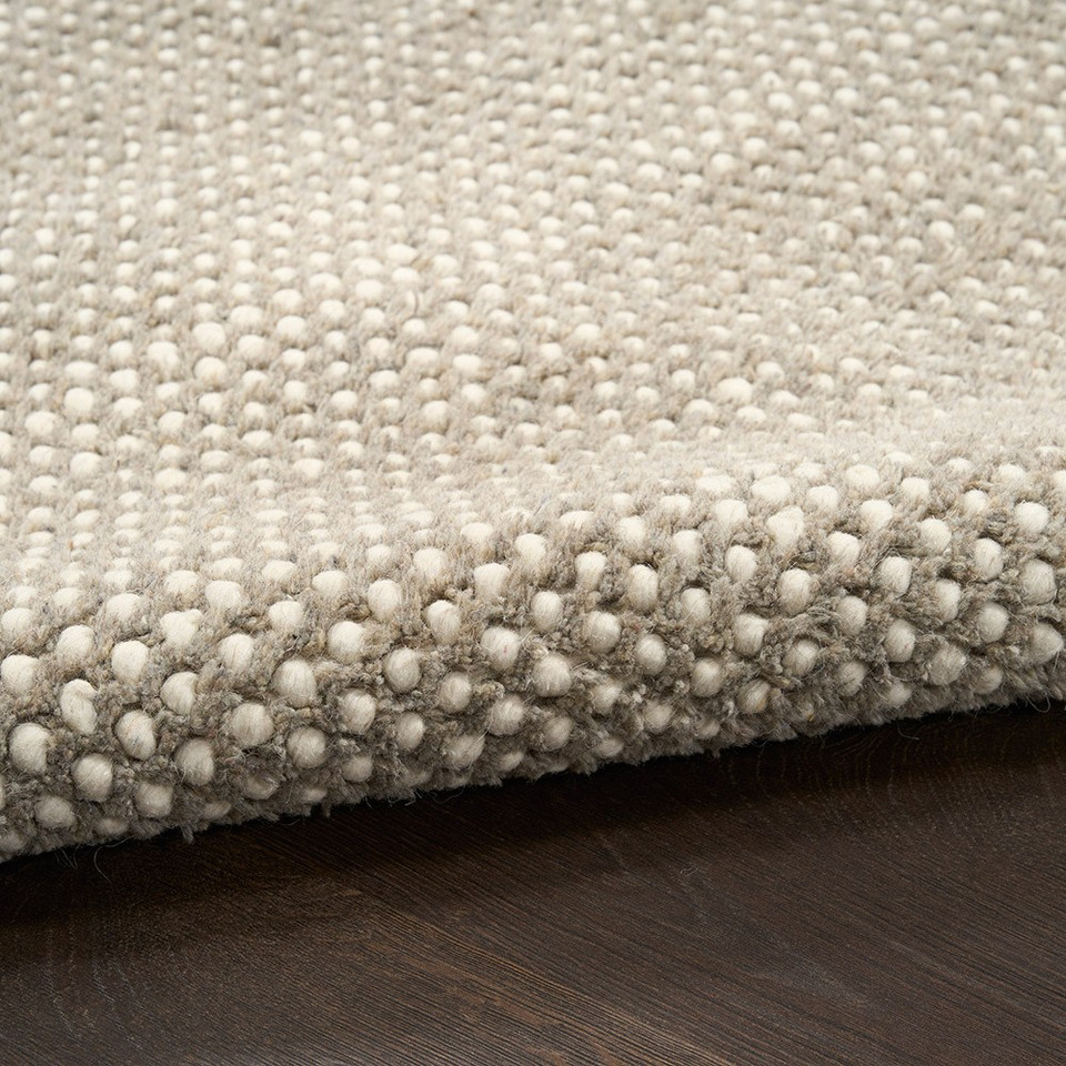 ivory grey rug partially rolled on wood floor