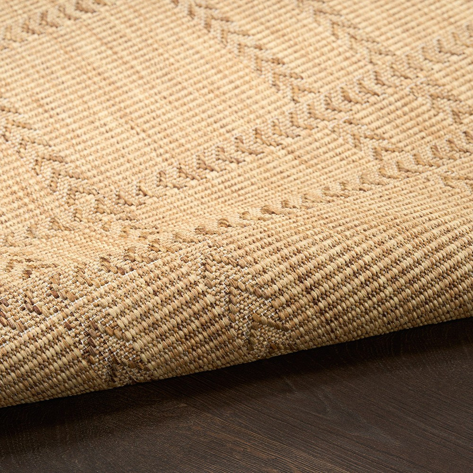 natural geometric indoor outdoor rug partially rolled on wood floor