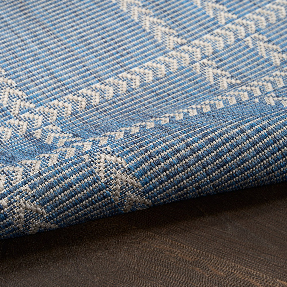 navy geometric indoor outdoor rug partially rolled on wood floor