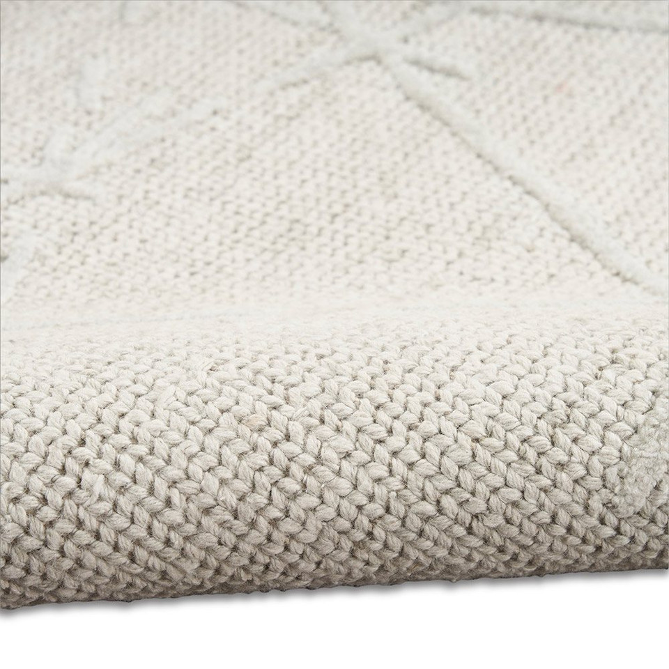 grey ivory calvin klein rug partially rolled on white floor