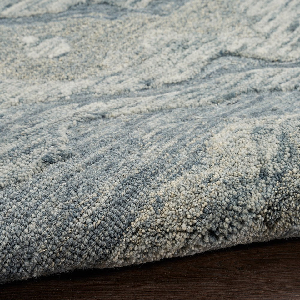 blue abstract rug partially rolled on wood floor