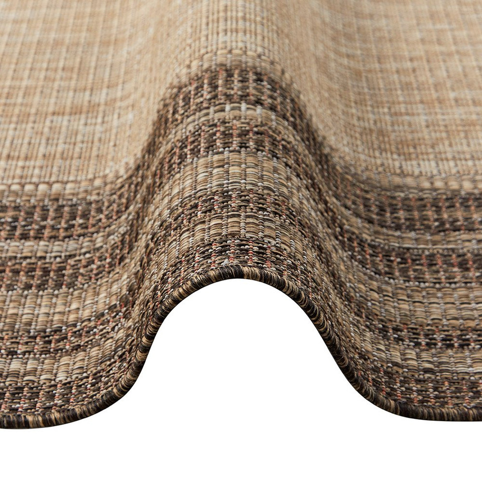 brown beige rug partially folded on a white floor