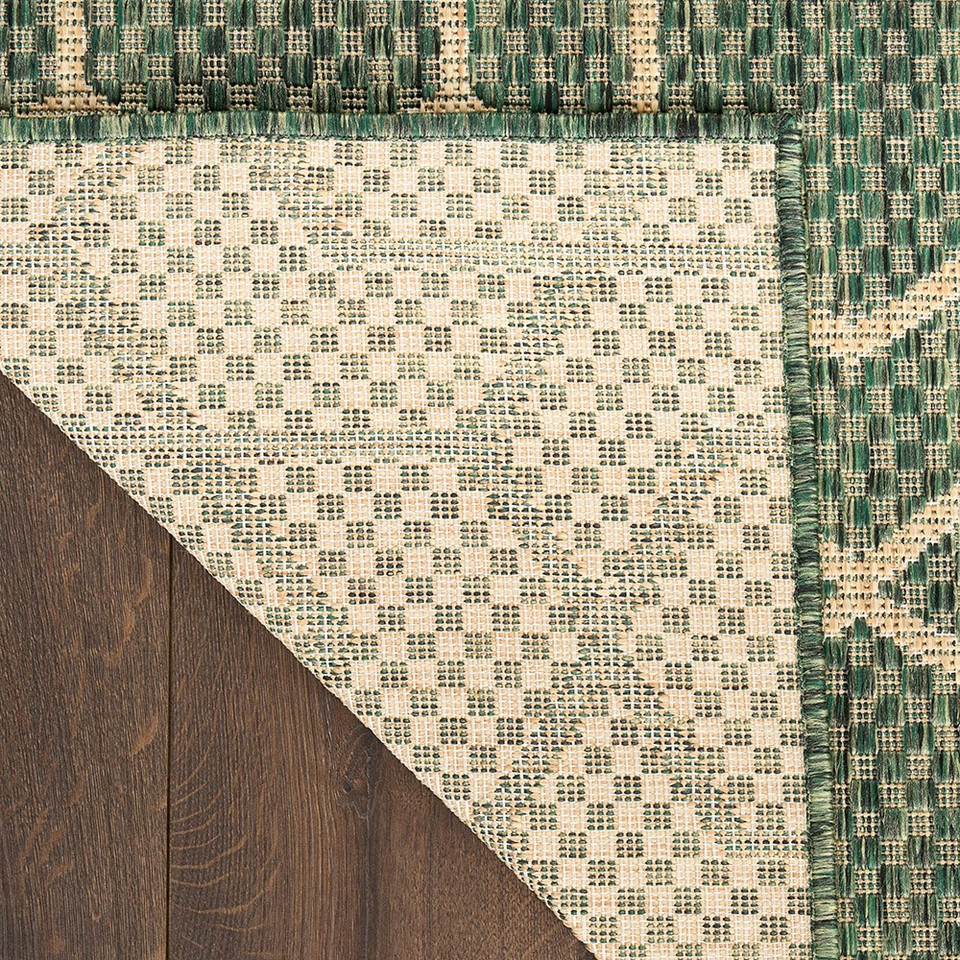 green geometric indoor outdoor rug folded on wood floor