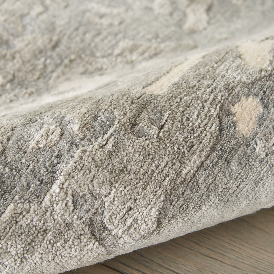 sand abstract rug partially rolled on wood floor