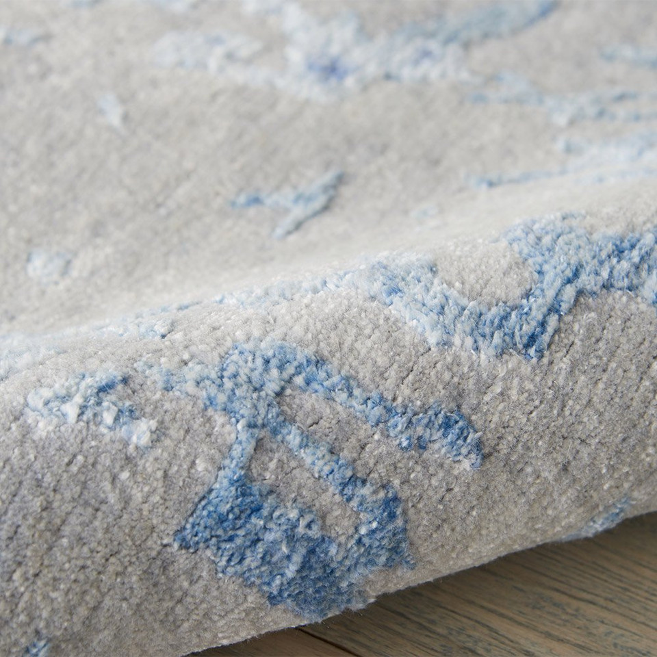 grey blue abstract rug partially rolled on wood floor