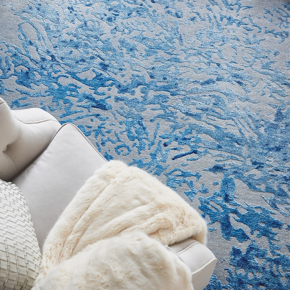 grey blue abstract rug with a matching sofa and throw