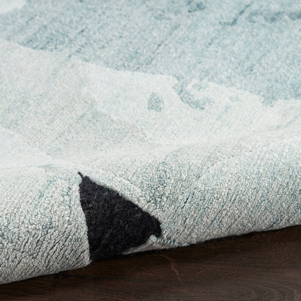 blue pink abstract rug partially rolled on wood floor