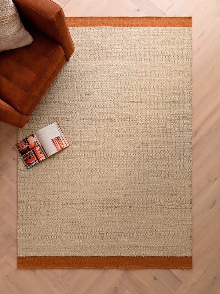 rust flatweave wool rug in a living room with matching decor
