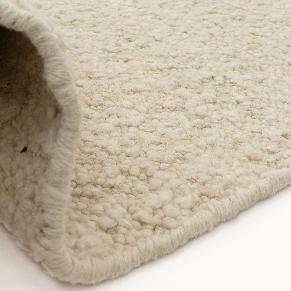 beige wool rug partial fold on white floor