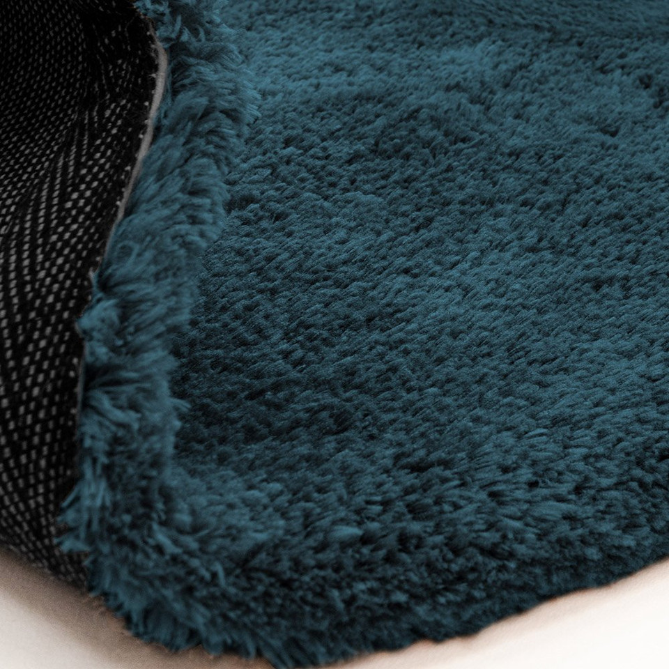 petrol shaggy rug partial fold on white floor