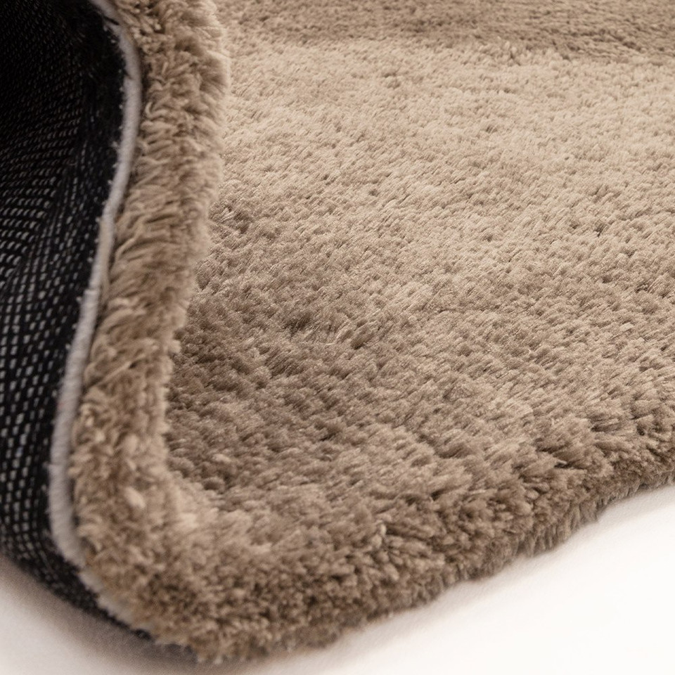 taupe shaggy rug partial fold on white floor