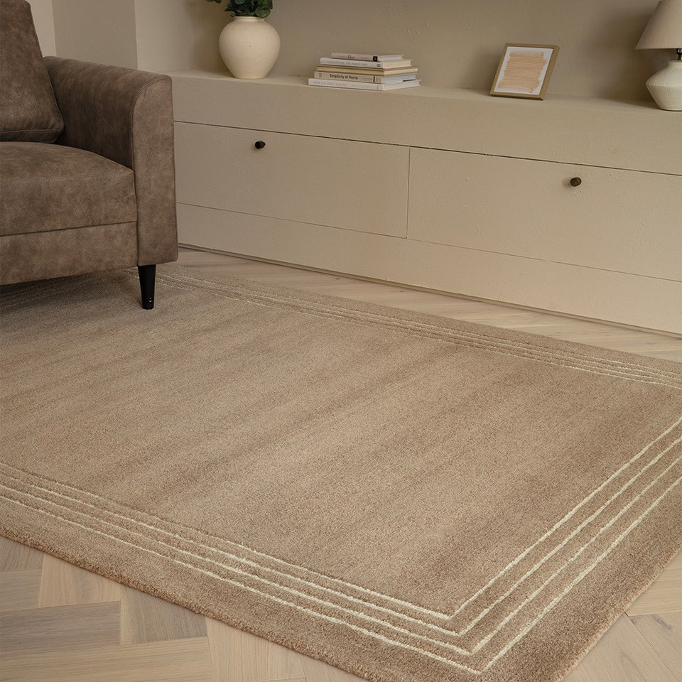 Modern living room setting featuring a luxury cocoa brown wool area rug on a herringbone hardwood floor next to a neutral console table.