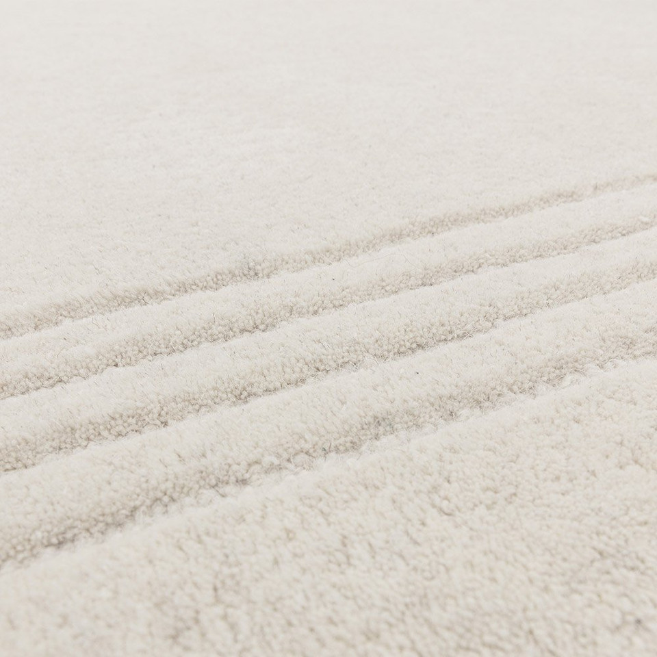 Macro texture shot showing the dense, high-quality tufted pile and soft fibers of a modern ivory wool area rug.