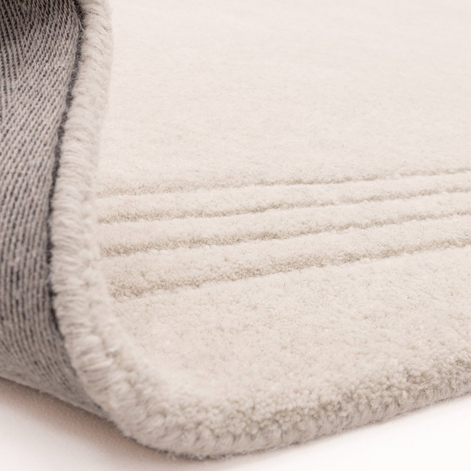 Flipped corner of the Orlo ivory wool rug, demonstrating the thick pile depth and a durable woven canvas backing.