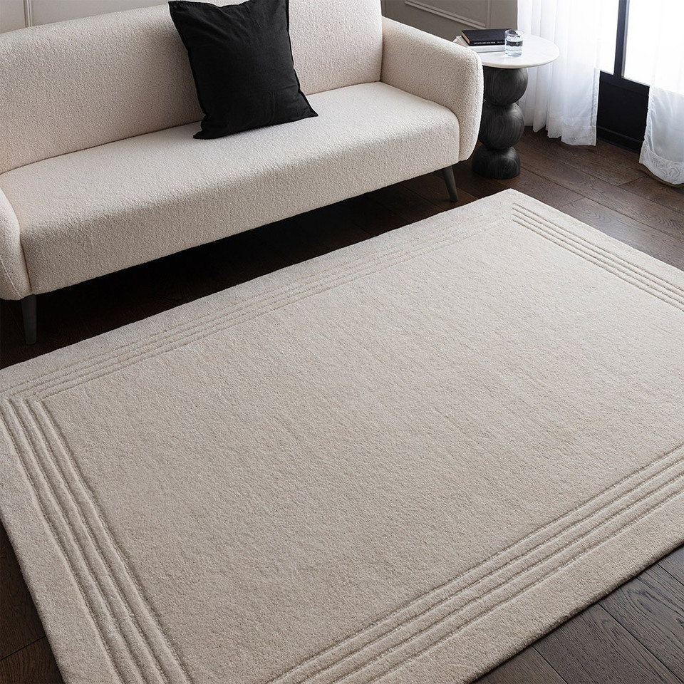 Bright, modern living room scene with a luxury ivory wool rug anchoring a contemporary sofa and minimalist home decor.