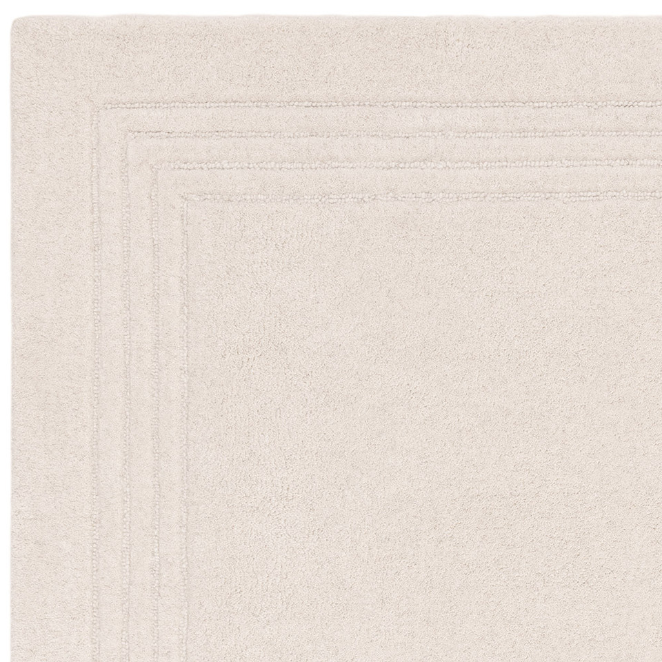 Overhead studio shot highlighting the neat rectangular corner and dark minimalist border design of an ivory wool rug.