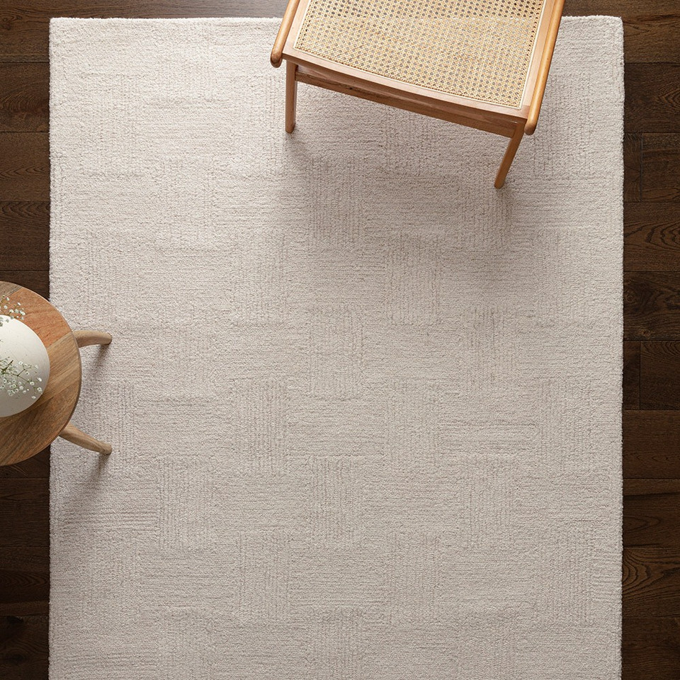 High-angle shot of the white and sand geometric wool rug spread out, showcasing its minimalist linear design for a modern home interior.