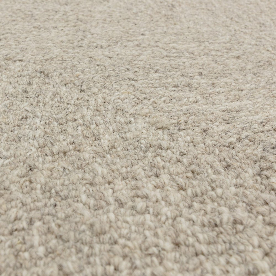 Macro texture shot showcasing the raised chevron pattern weave and soft premium fibers of a neutral sand wool area rug.
