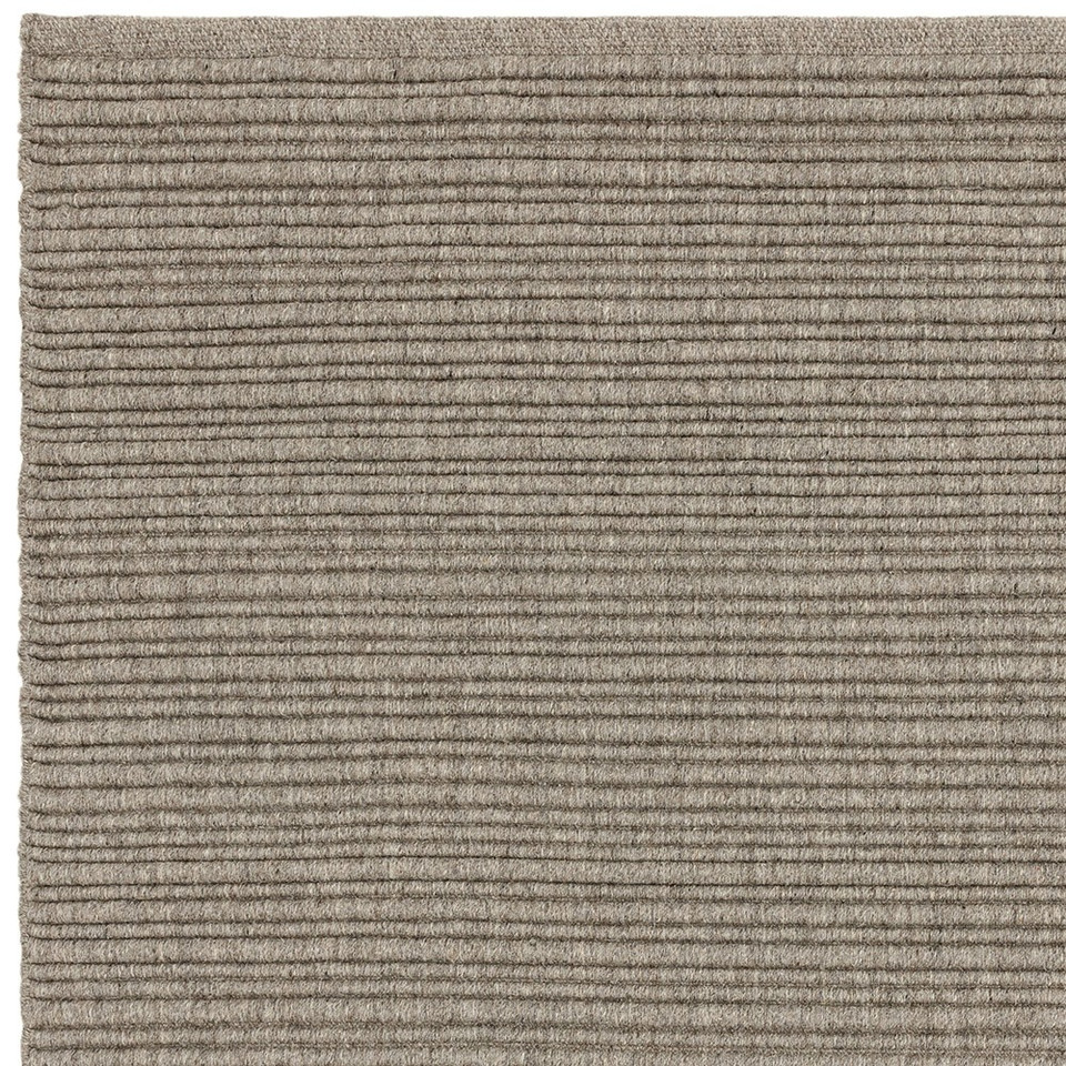 Clean corner finish of a neutral beige-gray woven wool rug with a distinct linear texture.