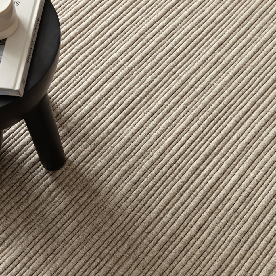 High-angle view of a textured ivory area rug highlighting its clean, linear geometric lines.