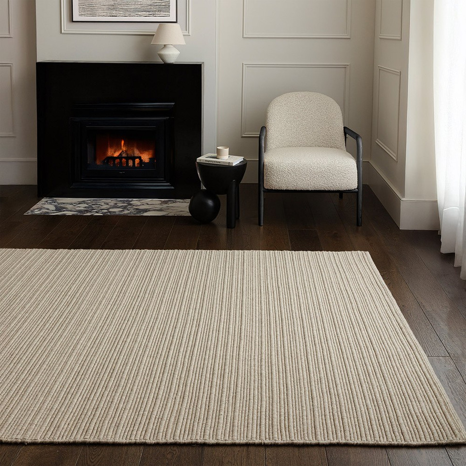 Minimalist living room setting featuring a cream-colored ribbed wool rug on dark wood flooring.