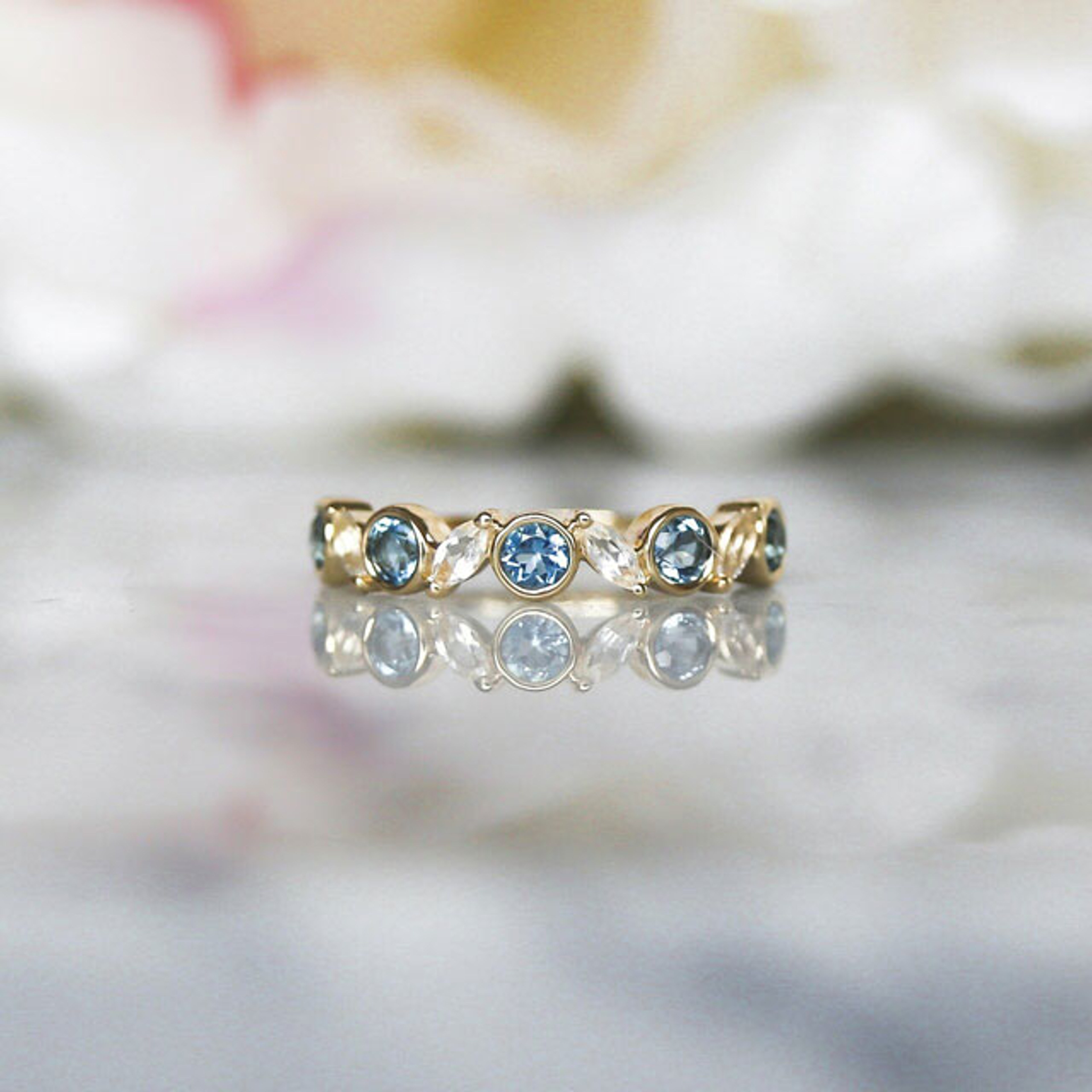 10K yellow gold stacking ring with alternating bezel set round blue topaz and marquise shaped white topaz