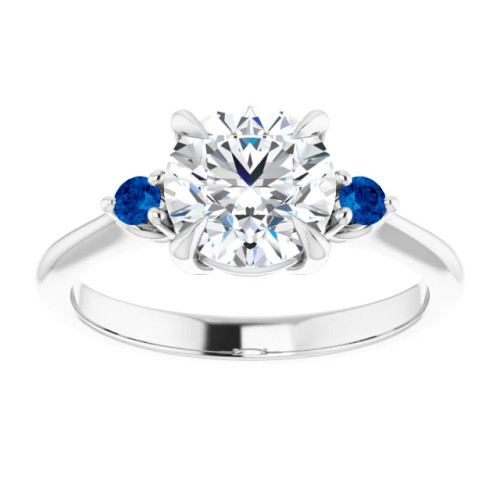 three stone engagement ring with round moissanite center stone and lab grown sapphire accent stones on each side with a polished band