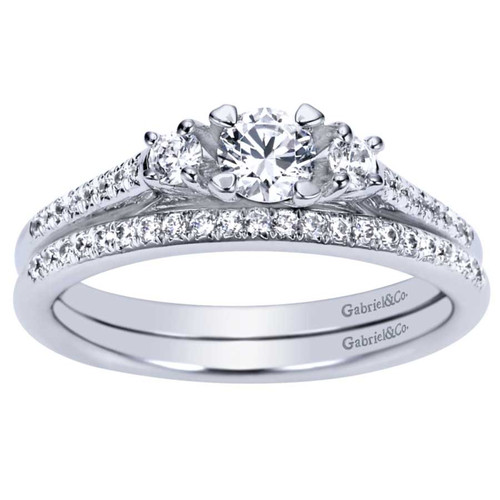 14K white gold three-stone engagement ring with round diamond center stone and side stones with diamond accented band and matching diamond wedding ring